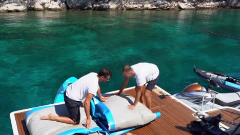 Young-men-folding-inflatable-boat-on-wooden-deck,-Plitvice-National-Park