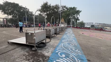 Toma-Cinematográfica-De-Múltiples-Etapas-De-Acero-Para-Ganga-Aarti-Mantenidas-En-La-Costa-De-Un-Río-Durante-La-Mañana-En-Kolkata,-India