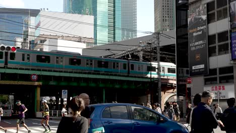 Daytime-capture-of-the-elevated-train-track-of-the-Tokyo-Metro-Tozai-Line-at-Shimbashi-Station-in-Japan-is-depicted,-with-vibrant-city-pedestrian-zones-and-visible-car-traffic