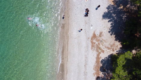 Un-Dron-Desciende-Hacia-Abajo-Para-Tomar-Una-Foto-De-Una-Familia-Disfrutando-De-Un-Día-En-La-Playa