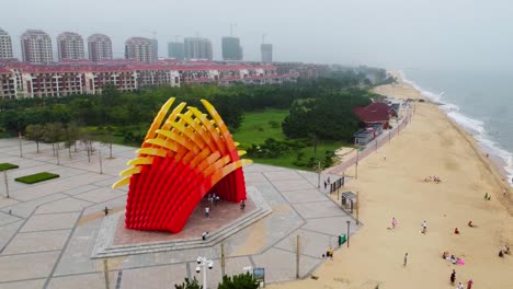 Slow-motion-aerial-orbit-view-of-a-beautiful-beach-monument-in-Nanhai,-China