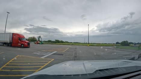 POV-–-Fahrt-über-Den-Parkplatz-Von-Walmart,-Vorbei-An-Mehreren-Schiffscontainern-An-Einem-Bewölkten,-Regnerischen-Tag