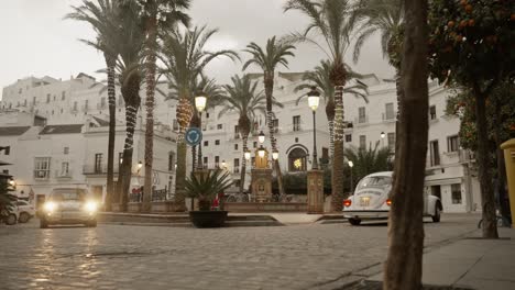 Coche-Escarabajo-Antiguo-Conduciendo-Por-Una-Plaza-En-Cámara-Lenta-En-Un-Hermoso-Pueblo-Blanco-En-España