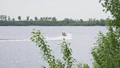 Una-Moto-Acuática-Navegando-Por-El-Lago,-Creando-Un-Chorro-De-Agua-Blanca-A-Su-Paso---Toma-Amplia-En-Cámara-Lenta