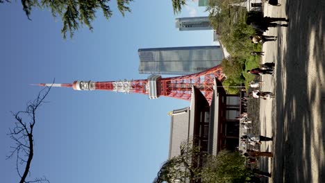 Visitantes-Caminando-Por-Terrenos-Al-Lado-Del-Templo-Zojoji-Con-Vistas-A-La-Torre-De-Tokio-Y-Las-Colinas-Azabudai-Contra-El-Cielo-Azul