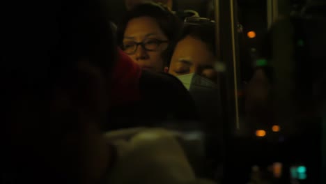 Man-with-face-mask-and-woman-with-glasses-in-glass-reflection-at-night