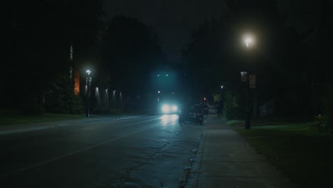 Calle-Suburbana-Oscuramente-Iluminada-Con-Un-Coche-Con-Faros-Al-Pasar