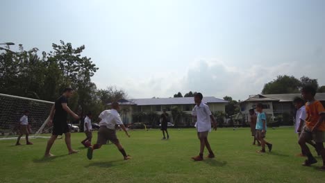 Niños-Felices-De-La-Escuela-Tailandesa-Jugando-Fútbol-También-Conocido-Como-Fútbol-Y-Anotando-Goles,-Vista-Cinematográfica-En-Cámara-Lenta