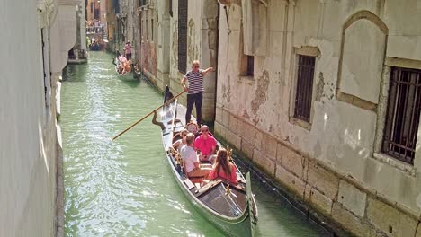 An-adventure-on-a-gondola-ride-through-narrow-canal-waterway-alley-in-Venice-Italy,-famous-tourists-activity