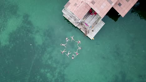 Aufsteigende-Luftaufnahme-Einer-Gruppe-Von-Freunden,-Die-Im-Wasser-Formen-Machen