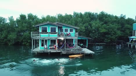 Toma-Aérea-De-Personas-Saltando-Desde-Un-Bungalow-Al-Agua-En-Panamá