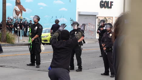 Hombre-Con-Las-Manos-Levantadas-Frente-Al-Bloqueo-Policial-En-Los-ángeles,-California,-Estados-Unidos,-Durante-La-Protesta-De-Vidas-Negras,-Pistolas-De-Balas-De-Goma,-Unidad-De-Respaldo-En-Segundo-Plano,-Cámara-Lenta