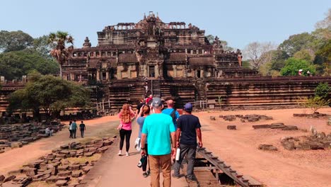 Gente-Caminando-Hacia-El-Templo-De-Ba-Phuon,-Deteniéndose-Para-Tomar-Fotografías-De-Su-Fachada