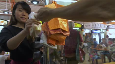 Woman-client-being-served-a-delicacy-in-Food-Market,-Singapore---Medium-detail-tracking-shot