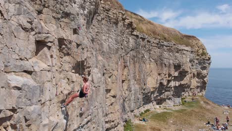 Young-Woman-Rock-Climber-Dangling-from-Cliff-Rope-by-the-Beach