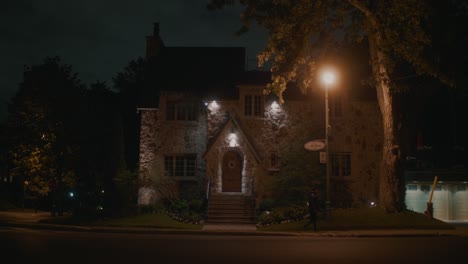 Adulto-Caminando-Por-Una-Casa-Oscura-Iluminada-Por-Una-Luz-Naranja-En-La-Calle-En-Montreal-Por-La-Noche