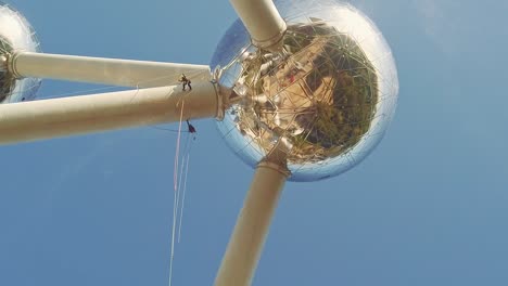 Vista-Panorámica-Horizontal-De-Trabajadores-De-Alto-Riesgo-Haciendo-Rappel-Y-Limpiando-La-Fachada-Del-Atomium-En-Bruselas,-Bélgica