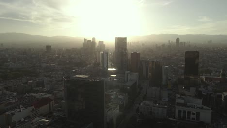 Paisaje-Urbano-Del-Centro-De-La-Ciudad-De-México,-Vista-Aérea-Cinematográfica-De-La-Luz-Del-Sol-De-La-Hora-Dorada-Y-El-Horizonte-Brumoso,-Disparo-De-Drones