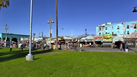 Famous-Venice-Beach-Boardwalk-with-people,-shops,-art-walls-in-Los-Angeles,-USA