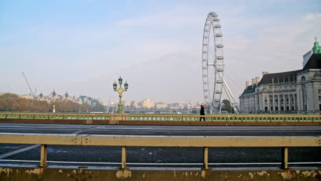 Carreteras-Tranquilas-Y-Vacías-En-La-Hora-Punta-En-Londres-En-El-Cierre-Del-Coronavirus-Covid-19-Con-Calles-Desiertas-En-El-Puente-De-Westminster-Y-El-Ojo-De-Londres,-Sin-Tráfico-Y-Una-Persona-Caminando-Para-El-Viaje-En-Hora-Punta