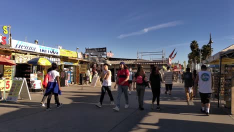 Spaziergang-Durch-Eine-Menschenmenge-Am-Venice-Beach-Boardwalk-Mit-Geschäften-Und-Ständen-An-Einem-Sonnigen-Nachmittag-In-Los-Angeles,-Kalifornien,-USA---Spaziergang