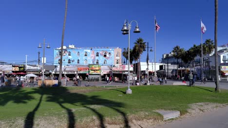 Tourists-walking-at-the-Venice-Beach-Boardwalk,-in-LA,-CA,-USA---pan-shot