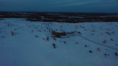 Vista-Aérea-Del-Restaurante-Tuikku,-Hora-Azul-En-Levi,-Laponia---Retroceso,-Disparo-De-Drone