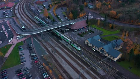 Vista-Aérea-De-Un-Tren-Vr-Que-Sale-De-Una-Pequeña-Estación-De-La-Ciudad,-Sombrío-Día-De-Otoño,-En-Finlandia---Dando-Vueltas,-Disparo-De-Drones