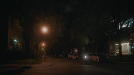 Calle-Oscuramente-Iluminada-En-Montreal-Con-Ciclistas-Que-Pasan-Con-Luces-De-Calle-De-Color-Naranja