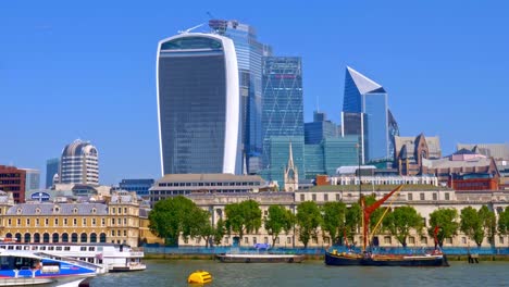 Static-shot-of-vintage-Thames-sailing-barge-and-Thames-clippers-cruising-passed-with-The-Walkie-Talkie-building-at-20-Fenchurch-Street-City-of-London-as-backdrop