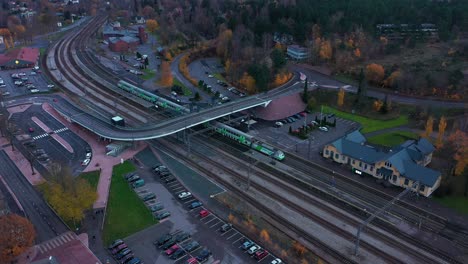 Vista-Aérea-De-La-Salida-De-Un-Tren-Vr-En-Una-Estación-De-La-Ciudad,-Día-De-Otoño,-En-Finlandia---Inclinación,-Disparo-Con-Drones