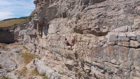 Toma-De-Drone-De-Una-Joven-Fuerte-Escalando-Rocas-En-El-Reino-Unido