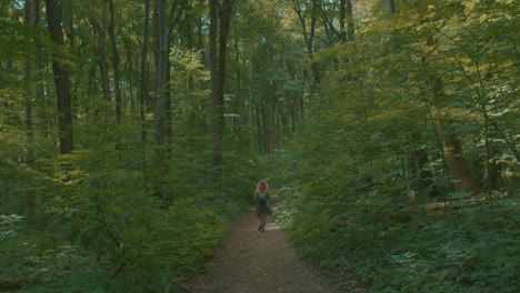 View-Of-Adult-Female-Walking-Down-Path-In-Green-Forest-In-Quebec,-Canada