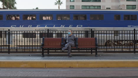 Uniformed-nurse-wearing-protective-face-mask-sitting-on-bench-waiting-for-train