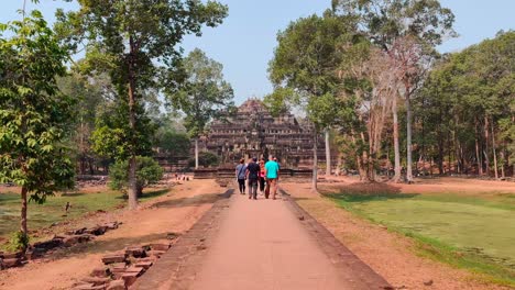 Caminando-Hacia-El-Templo-De-Ba-Phuon-Siguiendo-Un-Camino-Bordeado-De-árboles-En-Un-Día-Caluroso