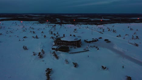 Vista-Aérea-Del-Restaurante-Tuikku,-Hora-Azul-En-Levi,-Laponia---Reversa,-Disparo-De-Drone