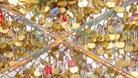 Nahaufnahme-Des-Vertikalen-Schwenks-Des-Symbolischen-Ausdrucks-Von-Liebe-Und-Zuneigung-Durch-Herzförmige-Vorhängeschlösser,-Die-An-Einen-Zaun-Vor-Dem-Sacre-Coeur-In-Paris,-Frankreich,-Gekettet-Sind