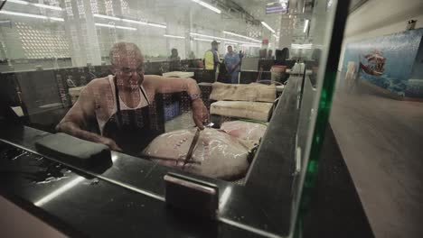 Fishmonger-cutting-open-a-Stingray-in-Fish-Market-in-Oman,-Middle-East---Wide-Slide-tracking-shot