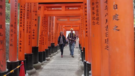 Tourists-visiting-the-red-shinto-shrines-with-japanes-text-on-it-in-Kyoto