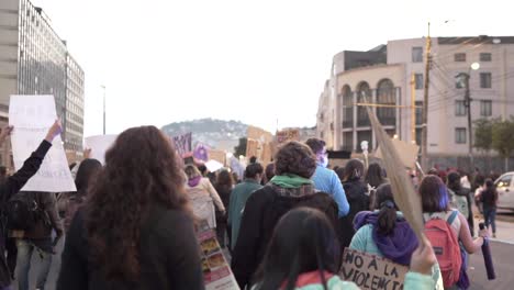 Women-march-while-holding-up-signs-with-protest-phrases-in-Quito,-Ecuador-during-the-International-Women's-day,-They-are-wearing-masks-due-to-covid-19-#8M