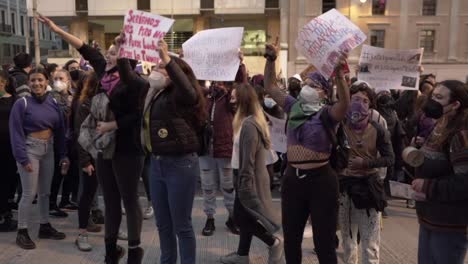 Several-women-are-jumping-and-singing-while-holding-up-protest-sings-during-the-International-Women's-day-in-Quito,-Ecuador