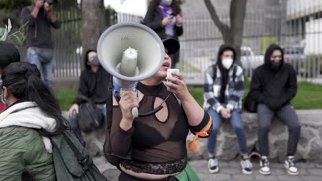 Eine-Frau-Mit-Mütze-Spricht-Während-Des-Protestes-Am-Internationalen-Frauentag-In-Quito,-Ecuador,-Durch-Ein-Megafon