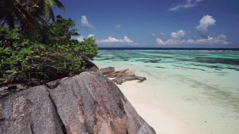 Drone-Volando-Sobre-Rocas-De-Granito-Revelando-A-Una-Dama-En-Traje-De-Baño,-Anse-Source-D&#39;argent,-Seychelles