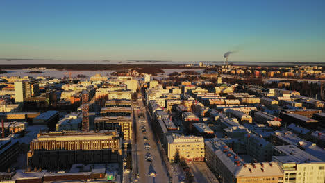 Vista-Aérea-De-La-Iluminada-Por-El-Sol,-El-Horizonte-De-La-Ciudad-De-Oulu,-Mañana-De-Invierno,-En-Finlandia---Dando-Vueltas,-Disparo-De-Drone