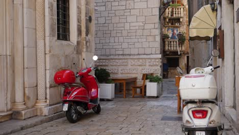 Old-narrow-street-with-two-parked-scooters,-slow-motion