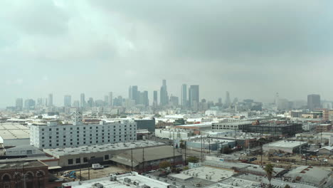 Centro-De-Los-Angeles,-California,-Estados-Unidos,-Vista-Aérea-De-Los-Edificios-Centrales-Bajo-Las-Nubes-Y-Aire-Contaminado-Del-Este,-Distrito-De-Arte-Con-Drones