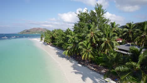 Drone-Volando-Sobre-La-Playa-De-Cote-D&#39;or-Cerca-De-Palmeras-Y-Restaurantes,-Seychelles