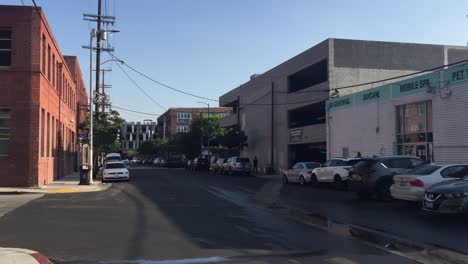 Coches-Estacionados-Fuera-De-Edificios-Comerciales-A-Lo-Largo-De-La-Calle-Húmeda-En-El-Distrito-De-Las-Artes,-Los-Ángeles