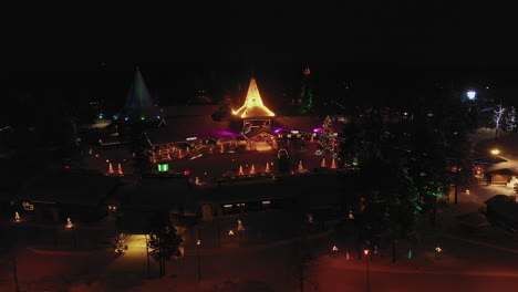 Vista-Aérea-De-Las-Luces-Navideñas-Iluminadas-Del-Pueblo-De-Santa-Claus-Por-La-Noche,-Disparo-De-Paralaje