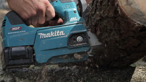 Cut-log-with-electric-handheld-chain-saw,-slow-motion